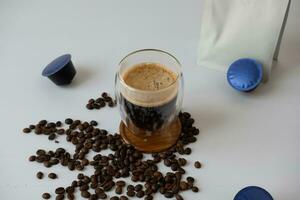 koffie mok met crema met koffie capsule elementen, koffie bonen, Aan een wit achtergrond. foto