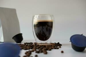 koffie mok met crema met koffie capsule elementen, koffie bonen, Aan een wit achtergrond. foto