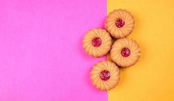 bovenaanzicht van jam koekjes op roze en gele achtergrond. sandwichkoekjes of geïsoleerde roomkoekjes. foto