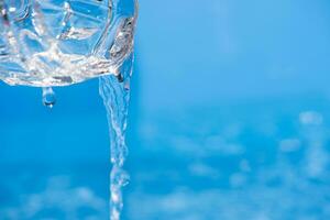 water vloeiende van een fles. water gieten in de glas. gieten water van fles in glas Aan blauw achtergrond. foto