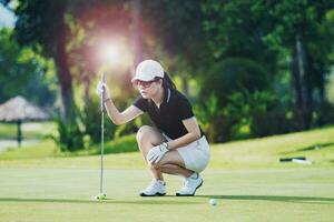 vrouw nadering voor op zoek golf zetten schot Aan groen golf gat foto