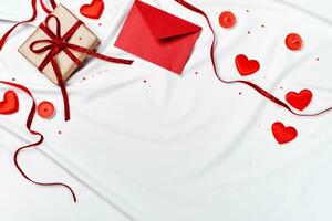 romantisch concept. valentijnsdag dag achtergrond. rood envelop, geschenk doos en harten Aan wit zijde vel foto