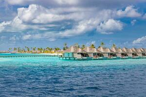 luchtfoto van het eiland maldiven, luxe watervilla's resort en houten pier. mooie hemel en oceaan lagune strand achtergrond. zomervakantie vakantie en reizen concept. paradijs lucht landschap pano foto