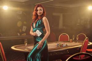 jong mooi vrouw is poseren tegen een poker tafel in luxe casino. foto