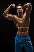 gespierd en fit jong bodybuilder geschiktheid mannetje model- poseren over- zwart achtergrond. foto