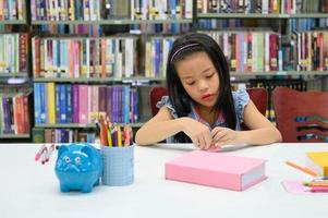 Aziatisch meisje vouwen en knutselen papier in bibliotheek tijdens kunstles. onderwijs en activiteitenconcept