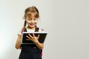 de weinig meisje gebruik makend van de tablet Aan de wit muur achtergrond foto