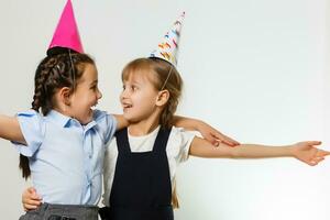 twee verjaardag meisjes in overhemd blauw school- uniform jurken hoed geïsoleerd Aan wit achtergrond kinderen studio portret. kinderjaren kinderen onderwijs levensstijl concept. bespotten omhoog kopiëren ruimte foto