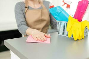 jong vrouw aan het doen huis klusjes. vrouw Holding schoonmaak hulpmiddelen. vrouw vervelend rubber beschermend geel handschoenen, Holding vod en verstuiven fles wasmiddel. zijn nooit te laat naar voorjaar schoon foto