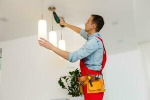 elektricien is installeren en Verbinden een lamp naar een plafond. foto