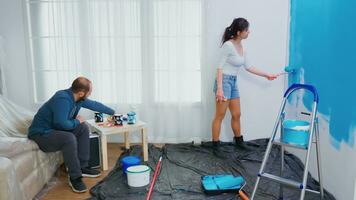 vrouw schilderij muur met rol borstel gedurende huis decoreren. paar in huis decoratie en vernieuwing in knus appartement vlak, reparatie en make-over foto