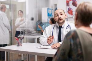 dokter uitleggen ziekte diagnose naar senior vrouw gedurende medisch overleg. volwassen arts bespreken ziekte behandeling met jong vrouw. foto