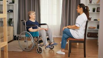 gehandicapten senior vrouw in rolstoel pratend met vrouw verpleegster. oud persoon pensioen huis, gezondheidszorg verpleging, Gezondheid steun, sociaal bijstand, dokter en huis onderhoud foto