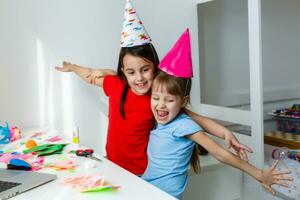 kinderen online verjaardag feest. weinig meisjes in jurken, hoed vieren vakantie met vrienden. conferentie, filmpje telefoontje in laptop, computer. quarantaine, coronavirus pandemisch covid19. foto