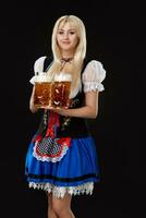 jong sexy vrouw vervelend een dirndl met twee bier mokken Aan zwart achtergrond. foto