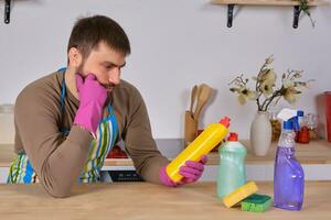 jong Mens gezocht naar helpen zijn vrouw in huis schoonmaken, maar hij niet weten wat naar Doen met allemaal van wasmiddelen foto