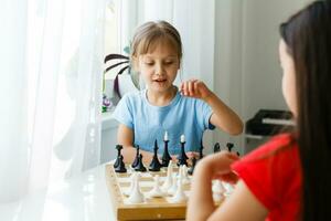 twee schattige kinderen die thuis schaken foto