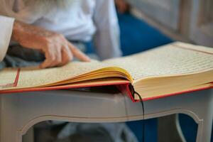 moslim Mens hand- Holding heilig boek koran Bij moskee foto