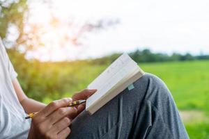 in een openbaar park schrijft een man met de hand in een klein wit memoblok om een aantekening te maken van iets dat hij niet wil vergeten of om een takenlijst voor de toekomst te maken. foto