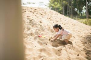 Aziatisch meisje kinderen spelen zand Aan de speelplaats in de cafe voor kinderen. weinig meisje spelen in de zand Aan de speelplaats. gezond actief baby buitenshuis Toneelstukken spellen concept. foto