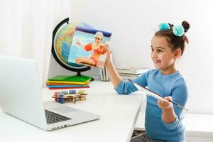 terug naar school. online onderwijs. slim school- meisje in klas. kinderjaren studie online. tekening les. kennis dag. klein meisje leerling met laptop. trek afbeelding met markeerstift. leven in digitaal leeftijd. foto