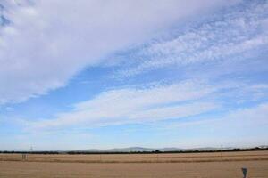 een veld- met een blauw lucht en wolken in de afstand foto
