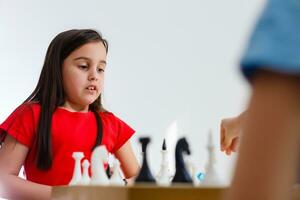 weinig meisje spelen schaak Bij een tafel foto