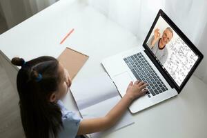 weinig meisje aan het studeren met laptop online aan het leren foto