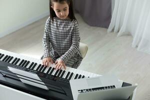 huis les Aan muziek- voor de meisje Aan de piano. de idee van activiteiten voor de kind Bij huis gedurende quarantaine. muziek- concept foto