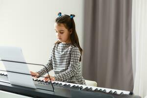 mooi meisje met lounge krullen spelen een piano in appartement foto