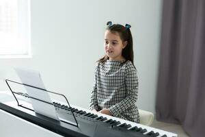 mooi meisje met lounge krullen spelen een piano in appartement foto