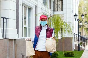 levering Mens Holding papier zak met voedsel Aan wit Ingang van huis achtergrond , voedsel levering Mens in beschermend masker foto