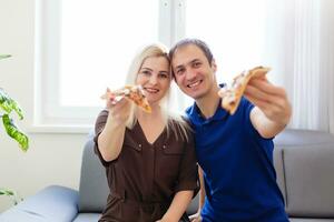 jong paar aan het eten pizza Bij huis foto