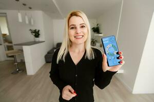 vrouw hand- Holding de telefoon met systeem knap huis foto