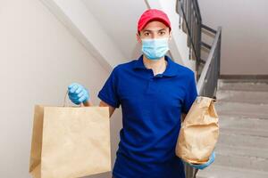 koerier in beschermend masker en medisch handschoenen levert meenemen voedsel. levering onderhoud onder quarantaine, ziekte uitbraak, coronavirus covid-19 pandemisch conditie. foto