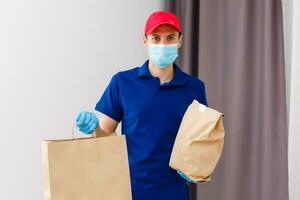 koerier in beschermend masker en medisch handschoenen levert meenemen voedsel. levering onderhoud onder quarantaine, ziekte uitbraak, coronavirus covid-19 pandemisch conditie. foto