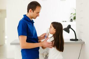 weinig kleuter meisje maken inademing met vernevelaar Bij huis. vader helpen en Holding de apparaat. kind hebben griep, hoesten en bronchitis. astma inhalator inademing stoom- ziek concept foto