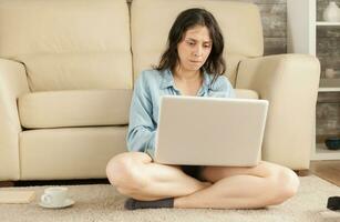 vrouw browsen Aan laptop zittend Aan leven kamer tapijt. foto