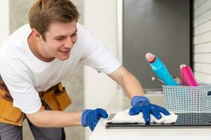 jong Mens is aan het doen sommige schoonmaak werk in de huis foto