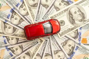 Amerikaans dollars en miniatuur auto model- Aan wit houten achtergrond. auto lening concept foto