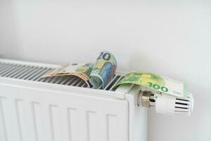 bankbiljet aan het liegen Aan de radiator, de concept van stijgende lijn energie prijzen en meer duur verwarming foto