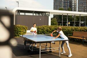 weinig meisje spelen tafel tennis in de tennis hal, tennis racket raken de bal, de toonhoogte van de bal. foto