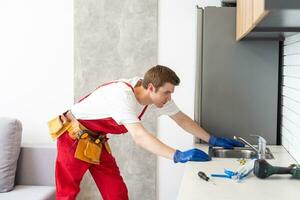 mannetje loodgieter reparatie wastafel kraan Bij cliënt huis. Mens monteur of klusjesman fix pijpleiding Bij klant keuken. mooi zo kwaliteit loodgieter bedrijf onderhoud. onderhoud en huishouden bijstand concept foto