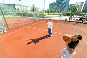 kinderen en sport. tiener- meisje spelen basketbal Aan de speelplaats. foto