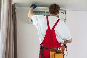 professioneel technicus onderhouden modern lucht conditioner binnenshuis. foto
