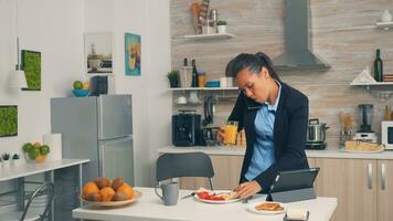 zakenvrouw Aan telefoon terwijl aan het eten ontbijt. geconcentreerd bedrijf vrouw in de ochtend- multitasking in de keuken voordat gaan naar de kantoor, stressvol manier van leven, carrière en doelen naar ontmoeten foto