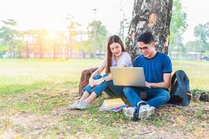 twee aziatische jonge universiteitsmensen discussiëren over huiswerk en eindexamen voor testen met laptop. onderwijs en vriendschap concept. geluk en leerconcept. liefhebbers en vriend thema