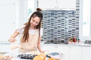 Aziatische vrouw koken en bakken taart in de keuken gelukkig alleen. mensen en levensstijlen concept. thema eten en drinken. interieur decoratie thema foto