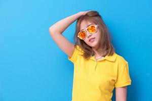 Aziatische vrouw mode poseren met mode bril op de blauwe achtergrond. vrouw met een geel poloshirt en een geeloranje bril. schoonheid en modern modeconcept. foto