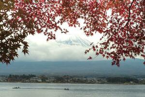selectief focus Aan de top van berg fuji met onscherp takken van herfst bladeren in voorgrond foto
